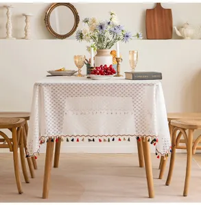 Close-up detail of white French lace tablecloth with vibrant hanging tassels and hollow mesh