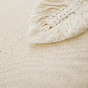 Close-up of handmade macramé leaf tassel on a neutral beige cotton canvas cushion cover