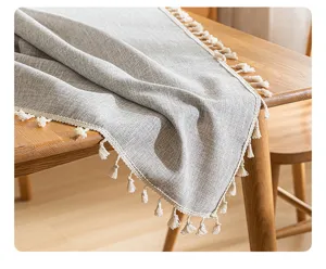 Primer plano de camino de mesa de lino sintético gris con elegantes borlas blancas