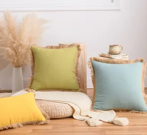 Gros plan sur des housses de coussin en coton et lin avec bordures décoratives à franges