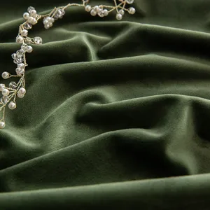 Luxurious dark green velvet curtain fabric showing soft texture and natural folds