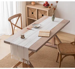 Eleganter cremeweißer Tischläufer mit Streifenmuster und Quasten auf Holztisch dekoriert