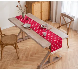 Camino de mesa rojo de algodón con patrón de estrellas y borlas en mesa de madera
