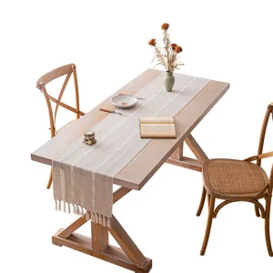 Boho-Tischläufer in Beige mit hohlen Streifenmustern und Quasten auf einem Holztisch