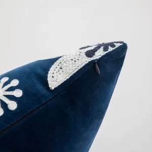 Detalle de funda de cojín de terciopelo azul con bordado floral y cremallera oculta