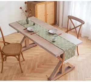 Camino de mesa de algodón verde con estrellas y borlas sobre una mesa de madera
