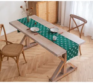 Camino de mesa de algodón verde oscuro con estrellas y borlas sobre mesa de madera