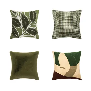 Lot de quatre housses de coussin vert artistique avec broderies et motifs.