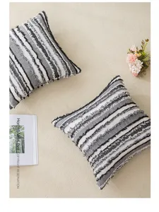Primer plano de funda de cojín boho con texturas de rayas grises y blancas.