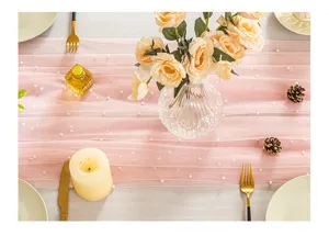 Detail view of pink gauze table runner with elegant pearl accents on a set table