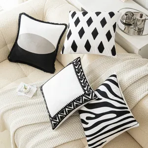 Set of 4 geometric embroidered black and white decorative throw pillow covers on a sofa