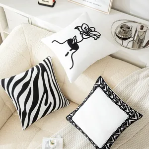 Set of minimalist black and white embroidered throw pillow covers on a cozy white sofa