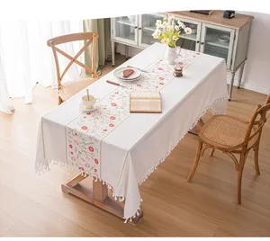 Tovaglia ricamata a fiori con nappe bianche su un tavolo da pranzo rustico in legno