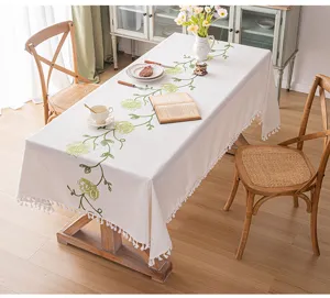 Tovaglia rettangolare rustica con ricamo floreale verde e nappe bianche su un tavolo