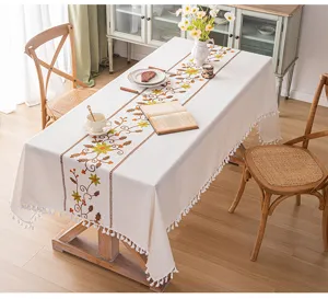 Dettaglio di una tovaglia in stile pastorale con ricamo floreale e nappe bianche decorative