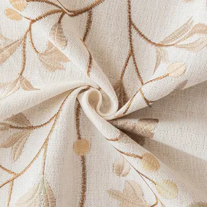 Close-up of elegant cream-colored tablecloth with golden floral embroidery and fabric texture.