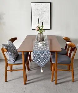 Chemin de table géométrique bleu et blanc avec glands sur table à manger en bois.