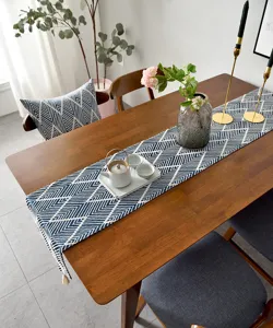 Détail du chemin de table jacquard japonais avec motif géométrique et glands blancs