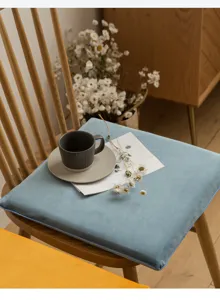 Primer plano de un suave cojín de asiento de terciopelo azul en una silla de madera.