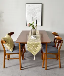 Vue détaillée d'un chemin de table en jacquard vert avec motif géométrique et glands blancs