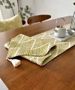 Détail d'un chemin de table jacquard géométrique vert olive avec pompon décoratif