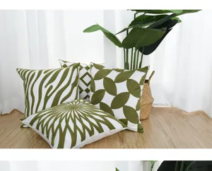 Close-up view of four green and white geometric embroidered pillow covers on wood floor
