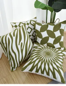 Detailed view of Nordic geometric green embroidered pillow covers on a wooden floor.