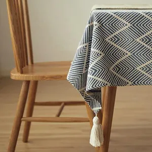 Primer plano del borde del mantel con diseño geométrico y una borla blanca decorativa