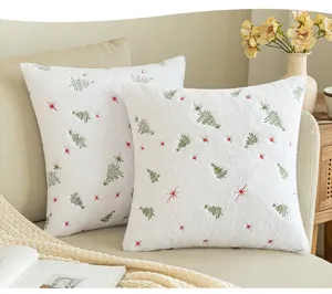 Detail of white plush Christmas pillow covers with embroidered tree and star patterns.