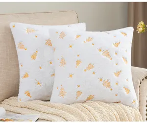 Detail of white plush pillowcase with golden Christmas tree embroidery for holiday decor.