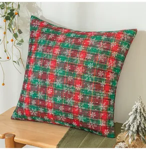 Weihnachtskissen mit rot-grünem Karomuster und Schneeflocken auf einer Holzbank