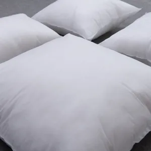Detalle de varios rellenos de cojín cuadrados blancos de tela no tejida para sofá.