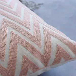 Housse de coussin moderne avec broderie chevron rose sur tissu de toile blanc.