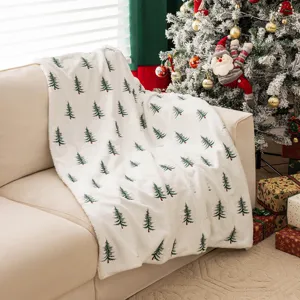 Zachte kerstdeken van imitatiekonijnenbont met geborduurde bomen op een beige bank.