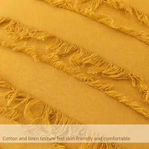 Detailansicht der Textur des gelben Baumwoll-Leinen-Kissenbezugs im Boho-Stil mit Quasten