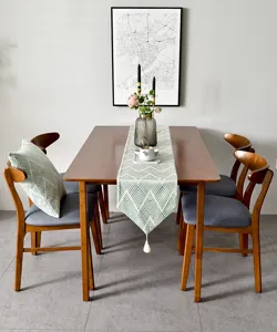 Détail d'un chemin de table jacquard japonais à motif chevron vert et pompon blanc