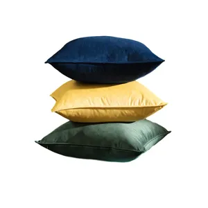 Stacked soft velvet cushion covers in navy blue, mustard yellow, and dark green.