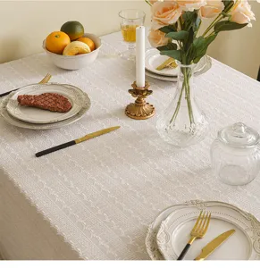 Detailed view of an elegant white lace tablecloth with embroidered floral patterns on a table
