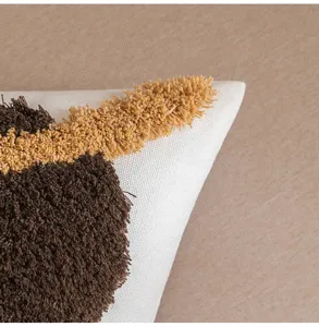 Detailaufnahme eines getufteten Boho-Kissenbezugs in Braun und Senfgelb mit Textur