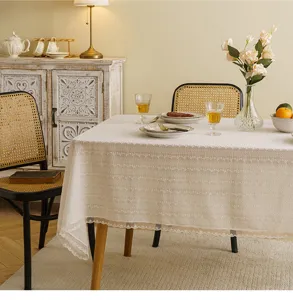 Close-up of elegant white lace tablecloth with floral embroidery and scalloped edges.