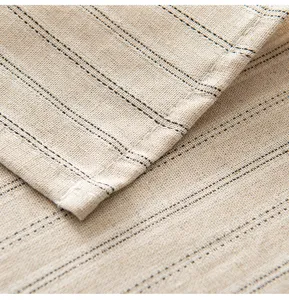 Dettaglio ravvicinato di tovaglia in lino beige con strisce nere e cuciture