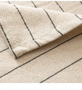 Dettaglio del tessuto in lino beige con sottili strisce nere sulla tovaglia