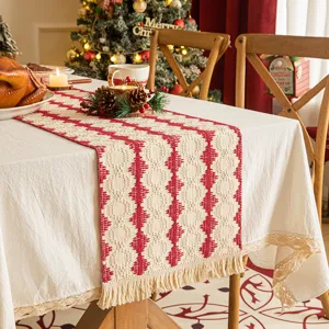 Red and cream woven Christmas table runner with fringes on a festive dining table