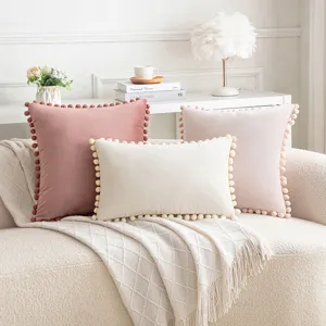 Fundas de cojín decorativas de terciopelo con pompones en suaves colores pastel.