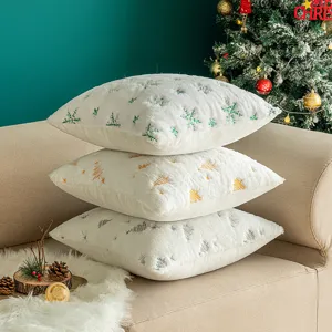 Three stacked white plush Christmas pillow covers with tree and snowflake embroidery.