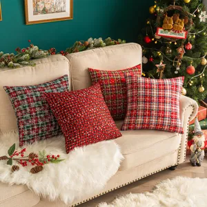 Rote und grüne Weihnachts-Dekokissen mit Karomuster und Schneeflocken auf dem Sofa