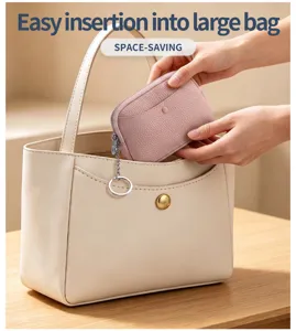 Kompakte rosa Ledergeldbörse wird zur Aufbewahrung in eine beige Handtasche gesteckt