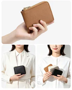 Detailed view of slim cross-grain leather coin purses in various colors held by a model.