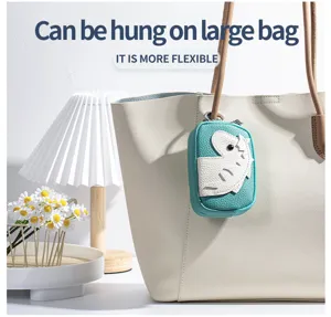 Detail of teal cartoon animal coin purse hanging on a beige leather tote bag handle
