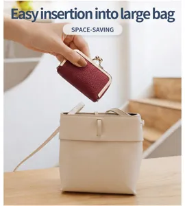 Kleine weinrote Kiss-Lock-Tasche wird leicht in eine größere beige Handtasche gesteckt
